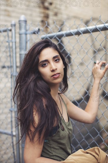 Mixed race woman standing at chain link fence