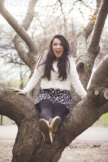 Hispanic woman sitting in tree