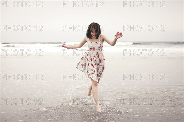 Caucasian woman running in waves on beach