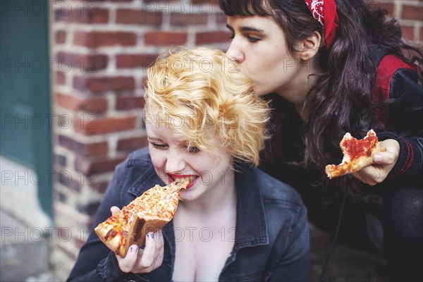 Caucasian women eating pizza outdoors