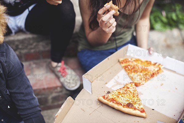 Women eating pizza on front steps