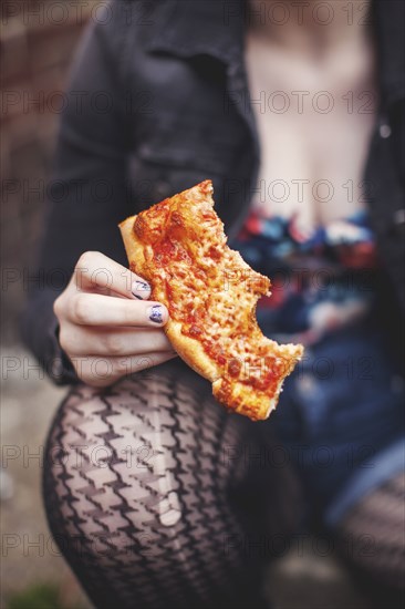 Close up of Caucasian woman eating pizza outdoors