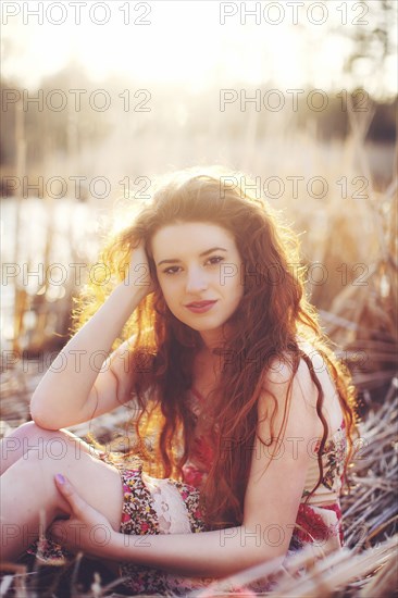 Hispanic woman sitting in tall grass in field