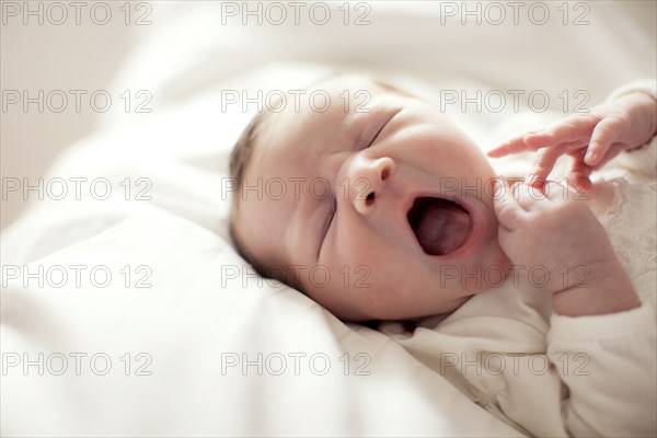 Caucasian baby girl yawning on bed