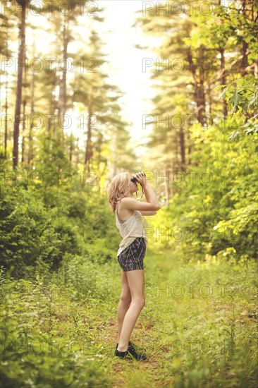 Caucasian woman using binoculars in forest