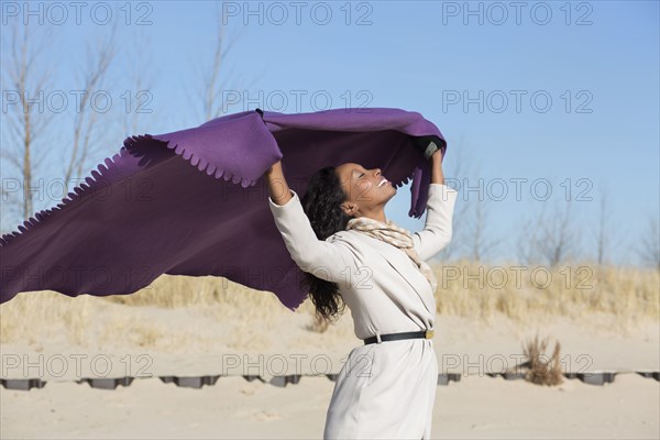 Woman playing with fabric on beach