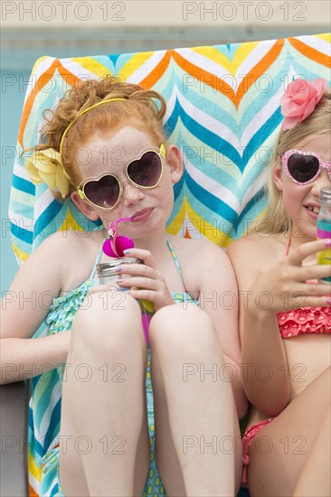 Caucasian girls sunbathing and drinking soda