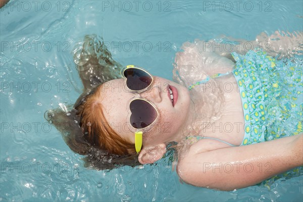 Caucasian girl floating in swimming pool