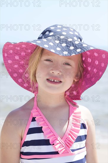 Caucasian girl wearing sun hat and bathing suit on beach