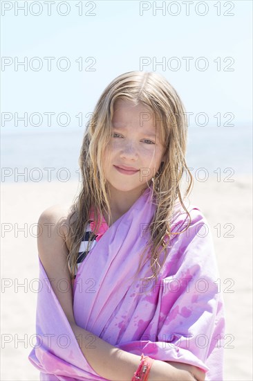 Caucasian girl wrapped in towel on beach