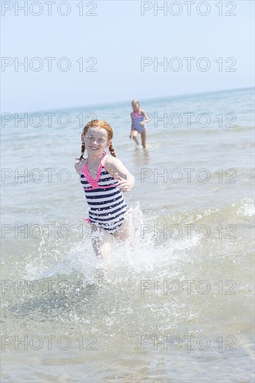 Caucasian girl splashing in waves on beach