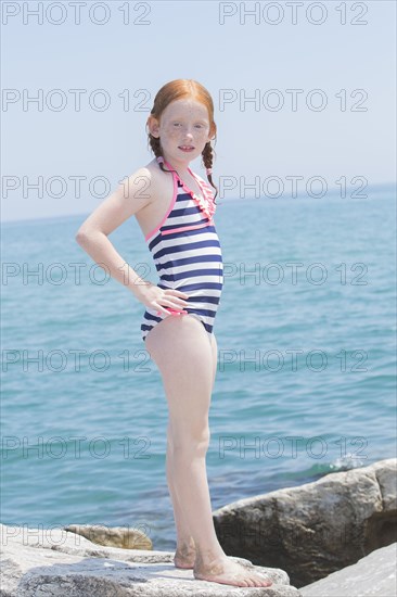 Caucasian girl standing on rocks on beach