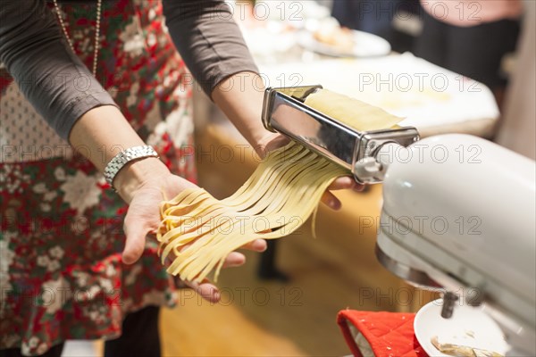 Woman rolling sheets of pasta in kitchen