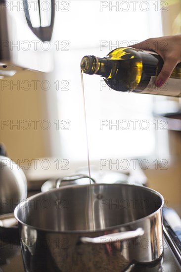 Close up of woman pouring olive oil into pot