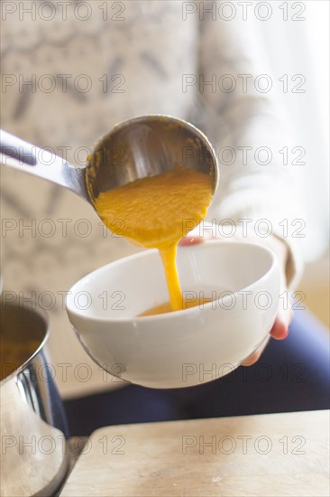 Close up of woman ladling bowl of soup