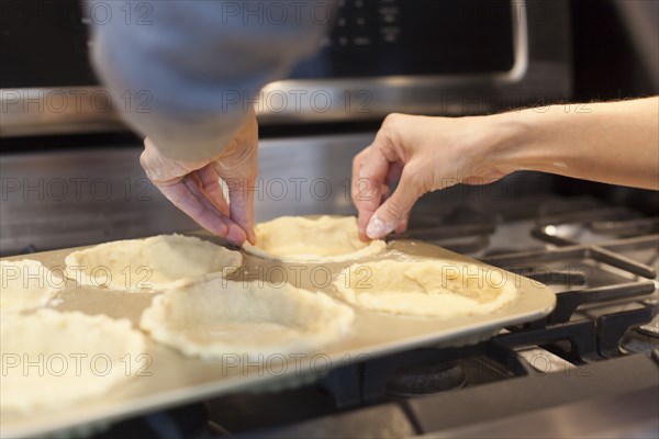 Close up of woman lining pie pans on stove