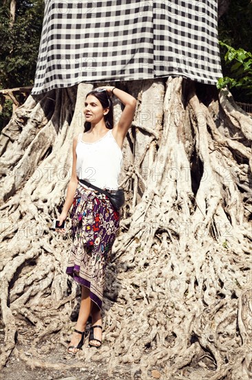 Woman standing on tree roots under fabric