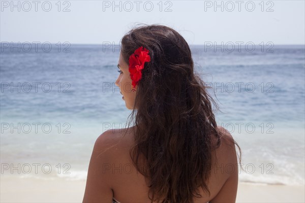 Rear view of woman wearing flower in her hair on beach