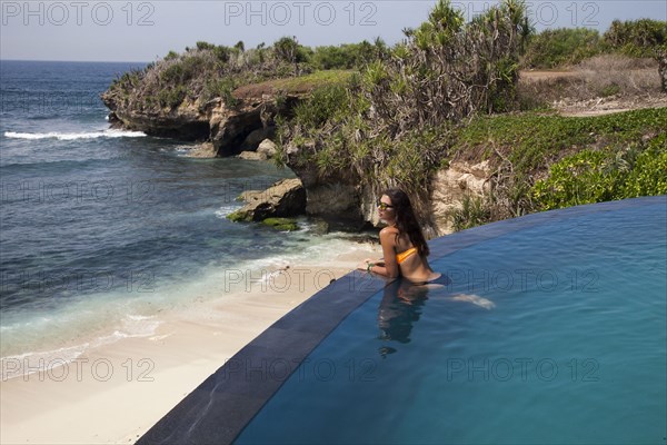 Woman admiring beach view from swimming pool