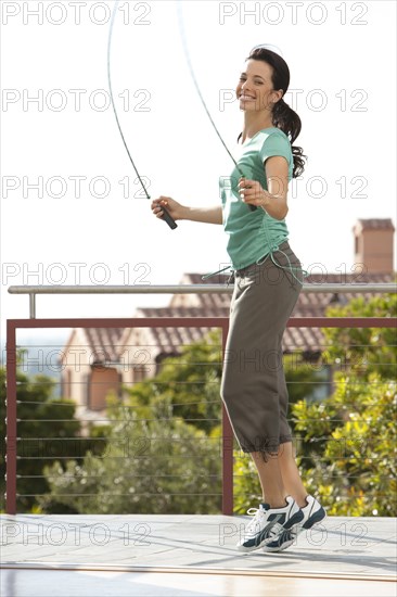 Caucasian woman jumping rope on urban rooftop