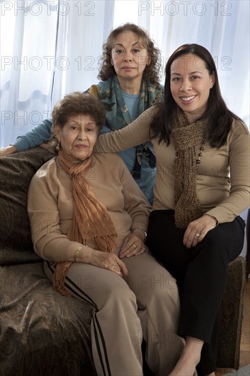 Three generations of women smiling on sofa