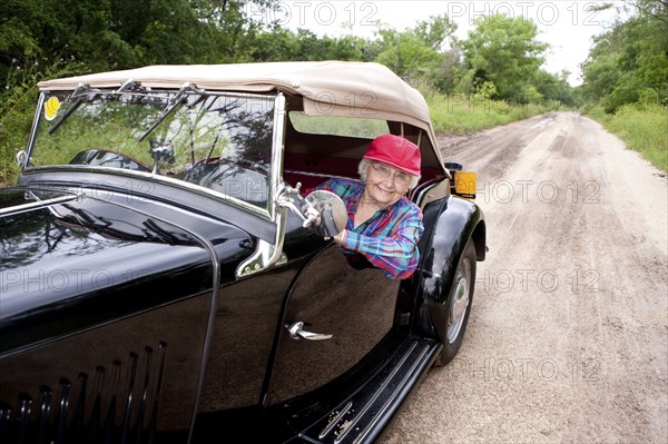 Older Caucasian woman driving convertible on rural road