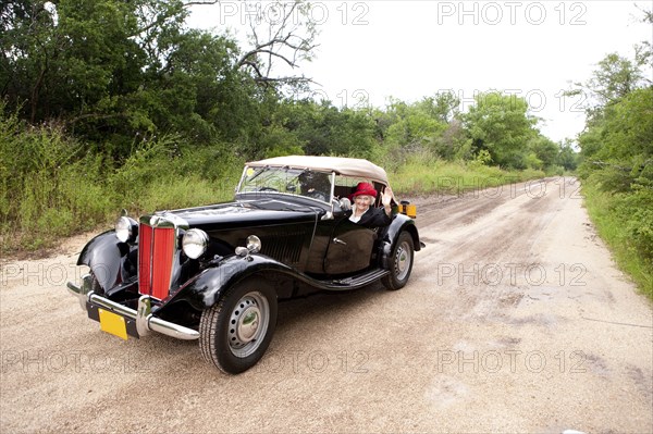 Older Caucasian woman driving convertible on rural road