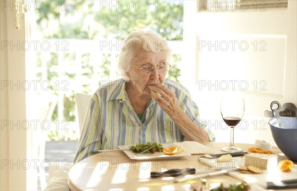 Older Caucasian woman eating lunch at table