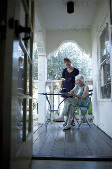 Granddaughter talking to grandmother on porch