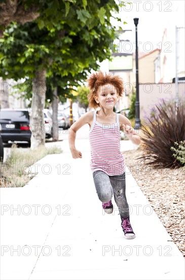 Smiling girl running on city sidewalk