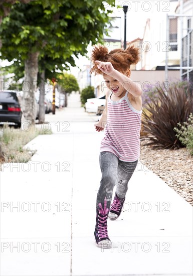 Smiling girl running on city sidewalk