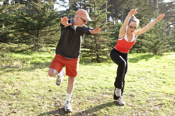 Caucasian man exercising with trainer in field