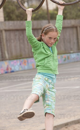 Caucasian girl playing on monkey bars at playground