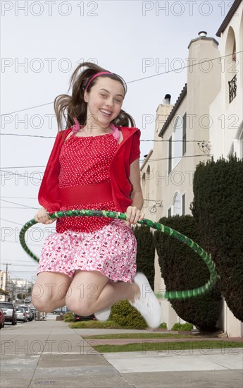 Smiling teenage girl jumping with plastic hoop