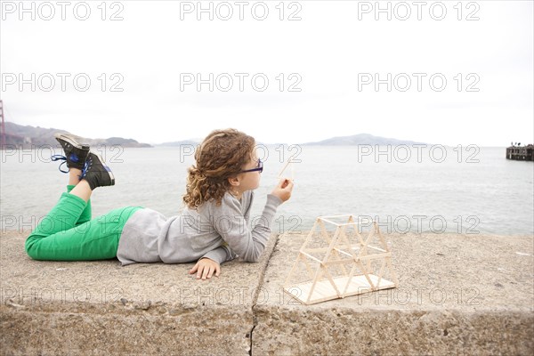 Caucasian girl examining homework project on wall over ocean