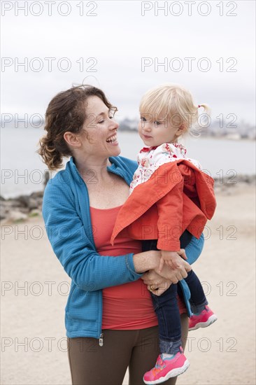 Caucasian mother holding daughter on beach