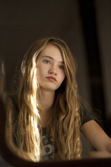 Serious teenage girl examining herself in mirror