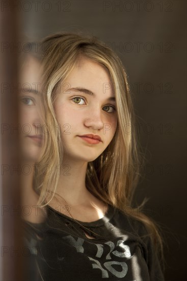 Serious teenage girl examining herself in mirror