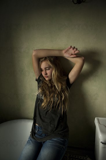 Serious teenage girl sitting in bathroom