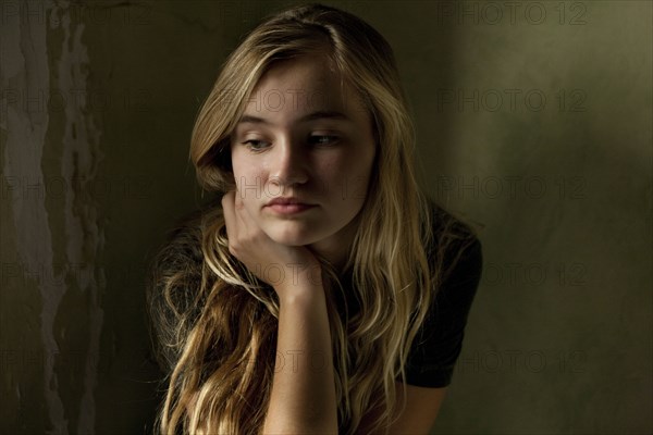 Serious teenage girl sitting by window