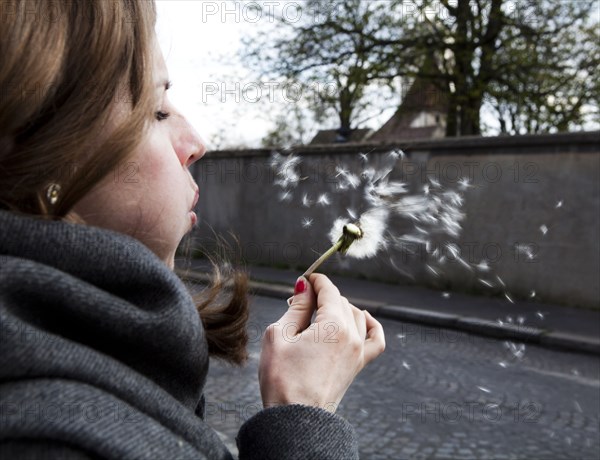 Close up of Caucasian woman blowing dandelion seeds