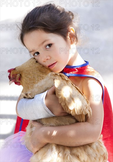 Mixed race girl hugging chicken