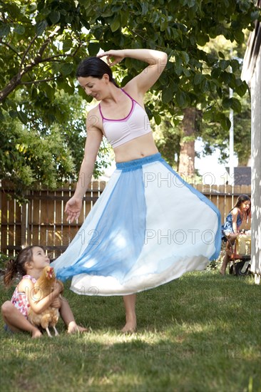 Mother and daughter dancing with chicken in backyard