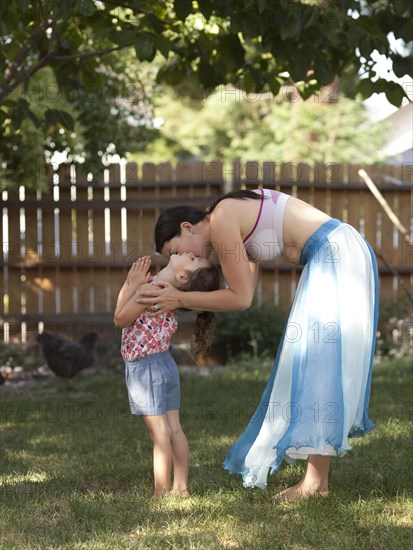 Mother and daughter hugging in backyard