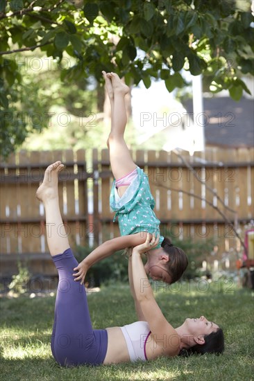 Mother and daughter practicing yoga in backyard