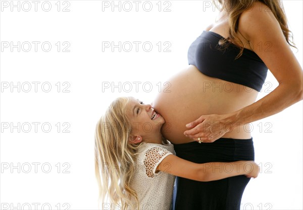 Caucasian girl hugging pregnant mother