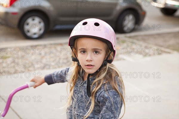 Caucasian girl riding bicycle on sidewalk