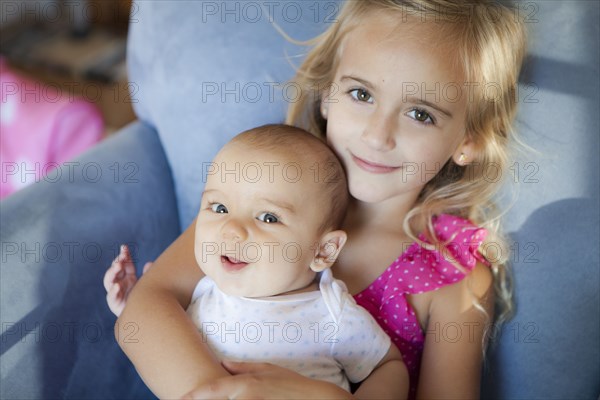 Caucasian brother and sister sitting in armchair