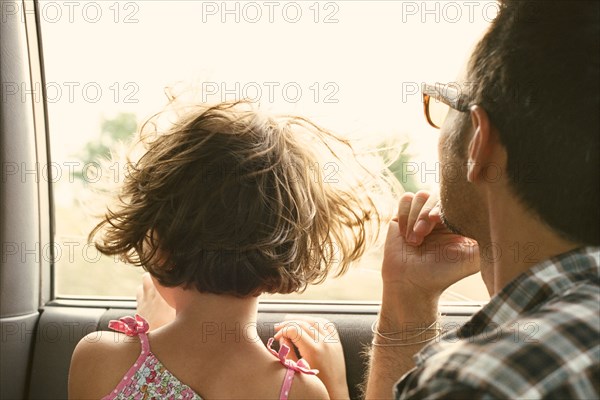 Father and daughter looking out car window