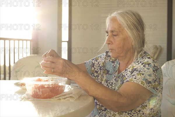 Older woman peeling fruit at table